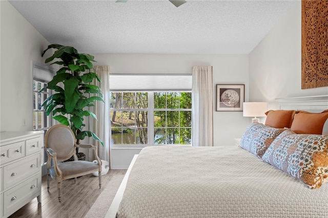 bedroom with light hardwood / wood-style floors and a textured ceiling