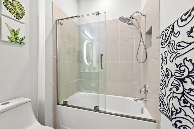 bathroom featuring toilet and shower / bath combination with glass door