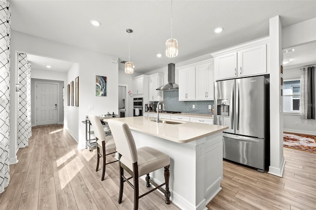 kitchen with stainless steel fridge with ice dispenser, white cabinetry, tasteful backsplash, wall chimney range hood, and pendant lighting