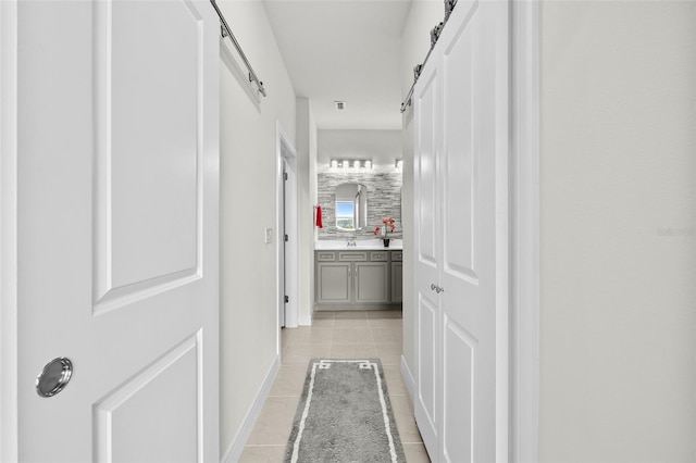 hall with light tile patterned flooring and a barn door