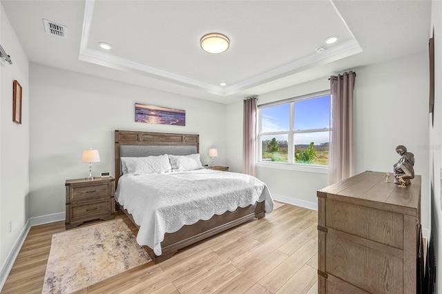 bedroom featuring light wood-type flooring and a tray ceiling