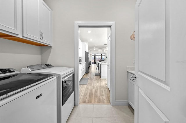 laundry room featuring cabinets, light tile patterned floors, and washing machine and clothes dryer