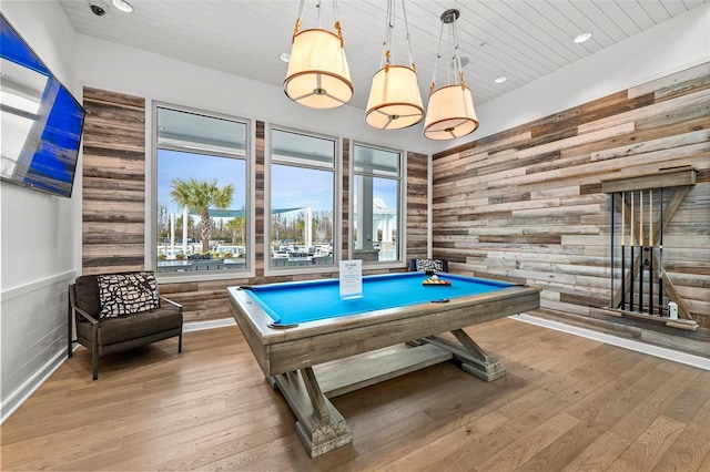 recreation room with light hardwood / wood-style floors, wooden walls, and billiards