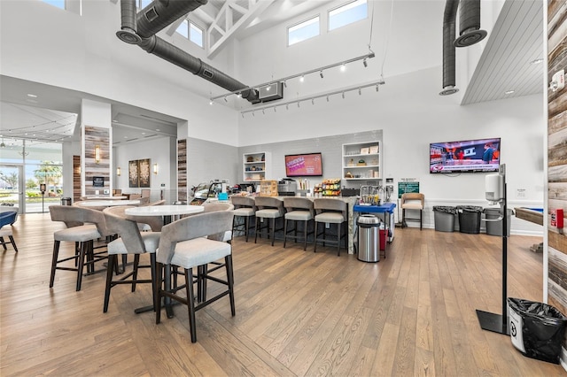 dining space featuring a towering ceiling and light hardwood / wood-style flooring