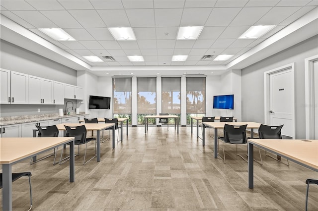 office space featuring a high ceiling, sink, and a drop ceiling