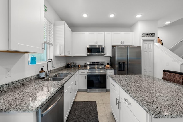 kitchen featuring white cabinetry, sink, light stone counters, and appliances with stainless steel finishes