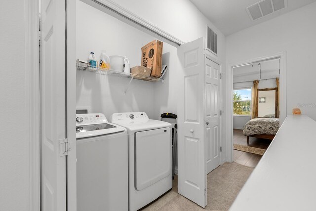 laundry room with light colored carpet and washing machine and clothes dryer