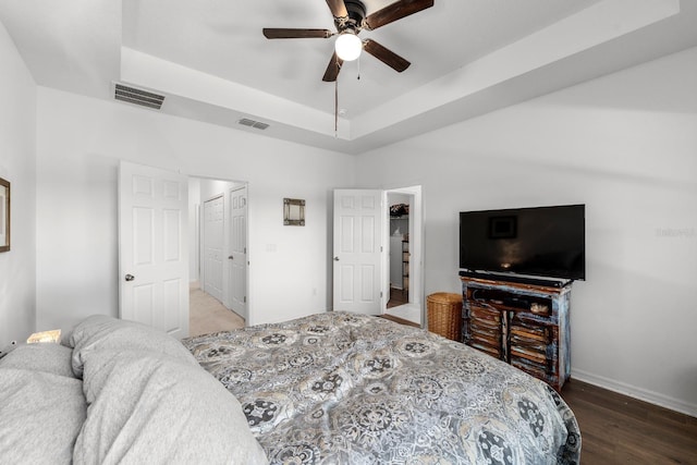 bedroom with a closet, a raised ceiling, ceiling fan, and dark hardwood / wood-style floors