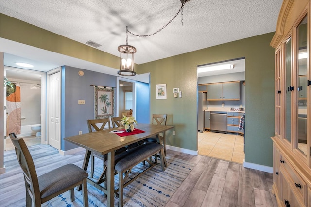 dining room featuring a chandelier, a textured ceiling, and light hardwood / wood-style flooring