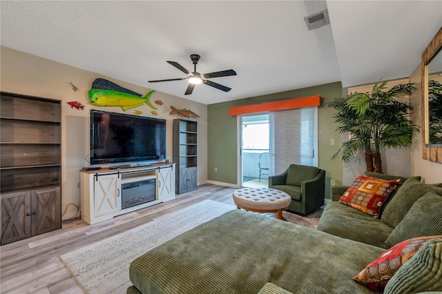 living room featuring ceiling fan, light hardwood / wood-style floors, and a textured ceiling