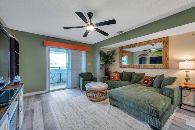 living room with a textured ceiling and light hardwood / wood-style flooring