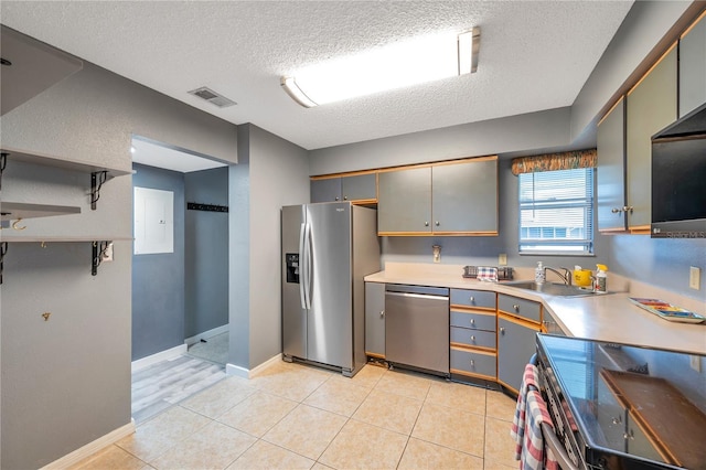 kitchen featuring sink, a textured ceiling, gray cabinets, light tile patterned floors, and appliances with stainless steel finishes