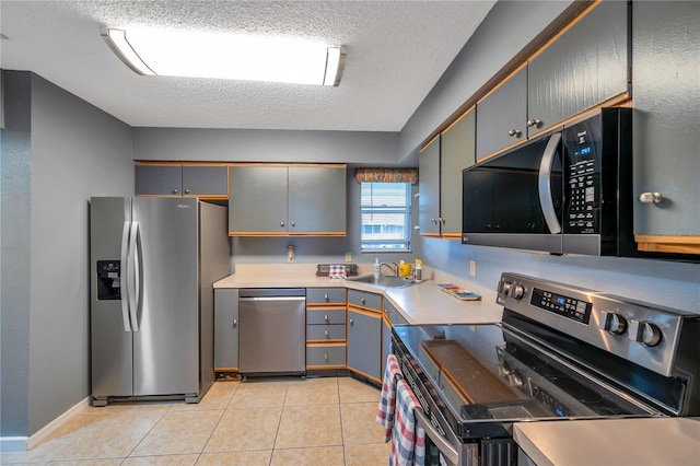 kitchen with appliances with stainless steel finishes, a textured ceiling, sink, gray cabinets, and light tile patterned flooring