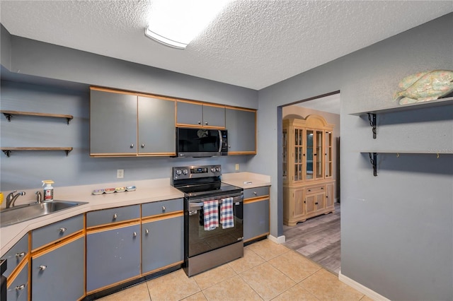 kitchen featuring stainless steel electric range, sink, gray cabinets, light tile patterned floors, and a textured ceiling