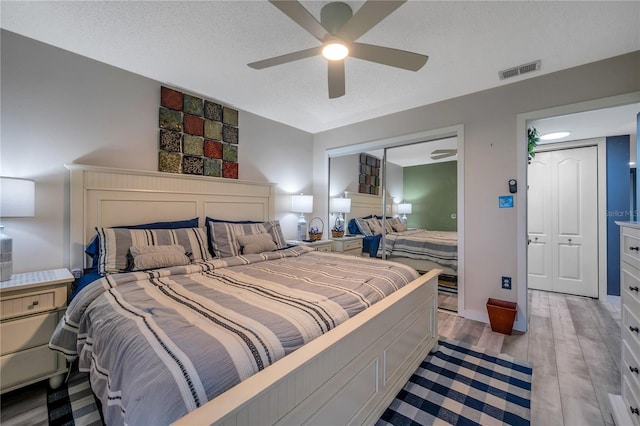 bedroom featuring a textured ceiling, a closet, light hardwood / wood-style flooring, and ceiling fan