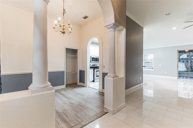 hall featuring ornate columns, crown molding, and a notable chandelier