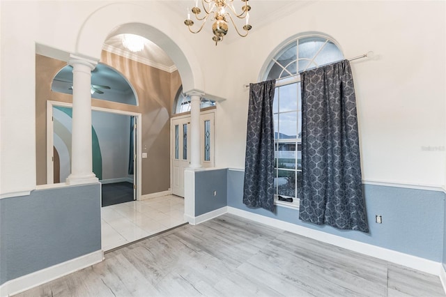 unfurnished room with hardwood / wood-style floors, ceiling fan with notable chandelier, ornamental molding, and decorative columns