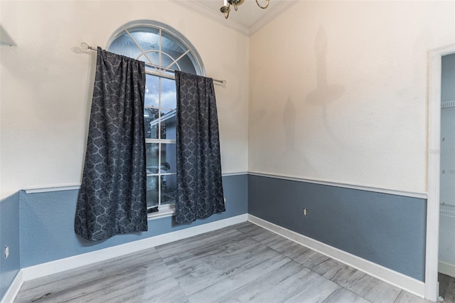 empty room featuring a chandelier, hardwood / wood-style flooring, and crown molding