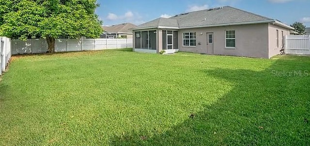 rear view of property with a sunroom and a lawn