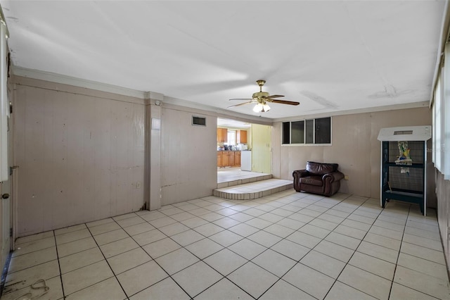 interior space with light tile patterned floors, ceiling fan, and wooden walls