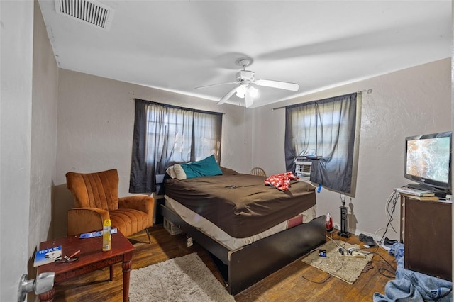 bedroom featuring ceiling fan, dark hardwood / wood-style flooring, and cooling unit