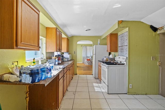 kitchen featuring washer / clothes dryer, white appliances, light tile patterned floors, and vaulted ceiling