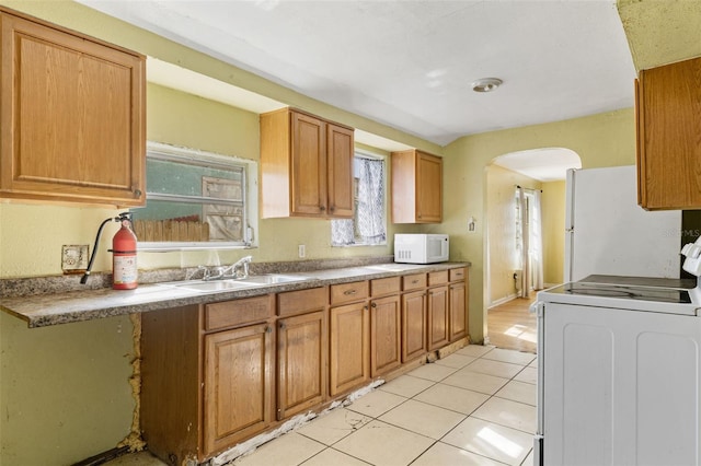 kitchen featuring sink, light tile patterned floors, and white appliances