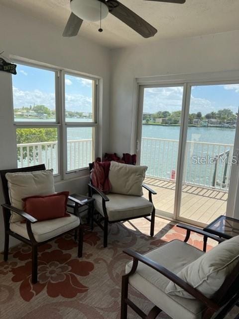 sunroom / solarium featuring ceiling fan and a water view