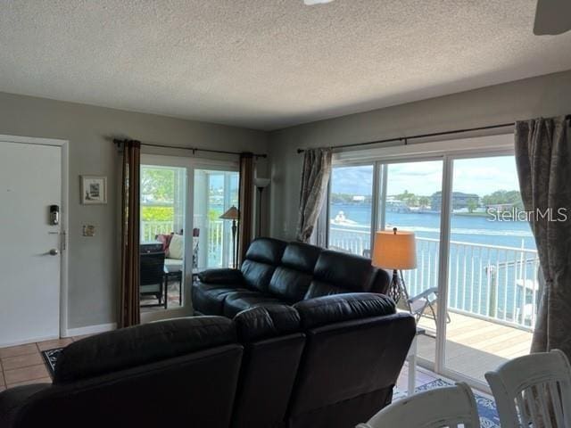 living room featuring tile patterned flooring, french doors, a textured ceiling, and a water view