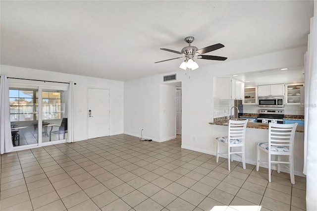 interior space with sink, light tile patterned flooring, kitchen peninsula, white cabinets, and appliances with stainless steel finishes