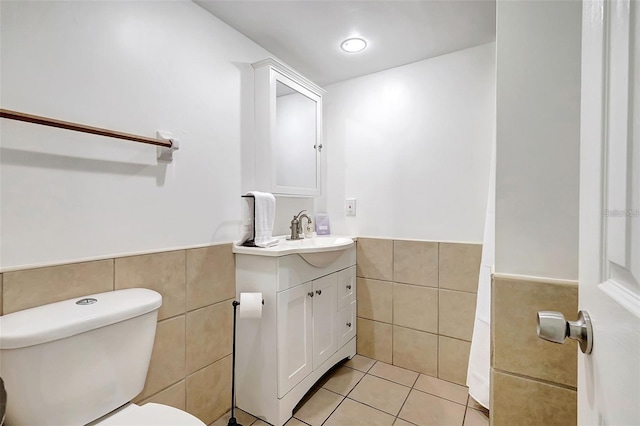 bathroom featuring tile patterned flooring, vanity, toilet, and tile walls