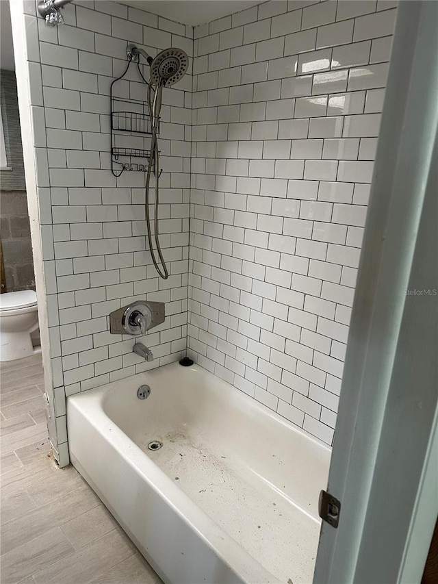 bathroom featuring toilet and tiled shower / bath