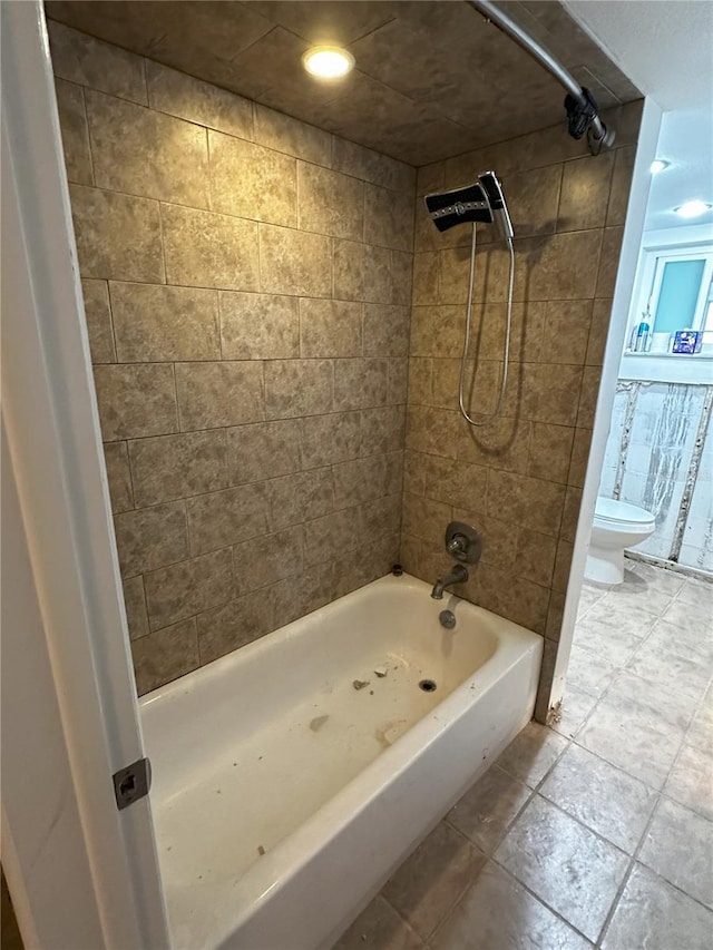 bathroom with tiled shower / bath combo and toilet