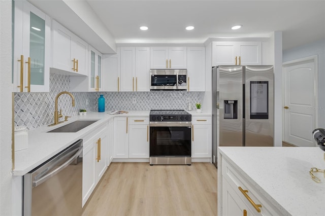 kitchen with white cabinetry, sink, stainless steel appliances, and light stone countertops