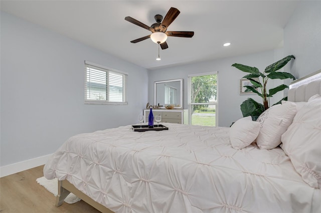 bedroom featuring ceiling fan, light hardwood / wood-style floors, and multiple windows