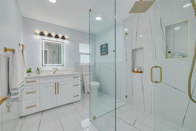 bathroom with tile walls, vanity, a shower with shower door, and toilet