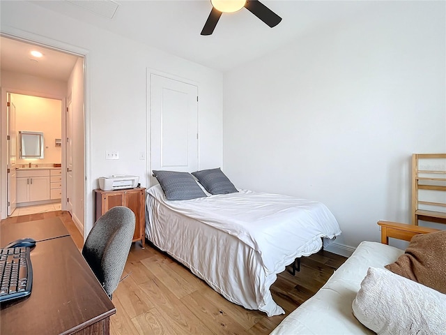 bedroom featuring connected bathroom, ceiling fan, sink, and light wood-type flooring