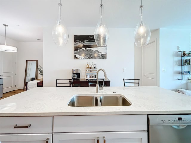 kitchen with white cabinets, a center island with sink, sink, light stone countertops, and dishwashing machine