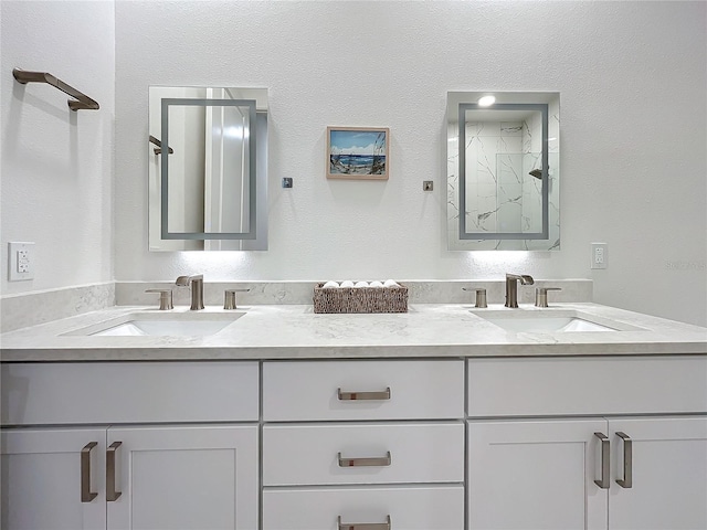 full bathroom featuring double vanity, a shower, and a sink