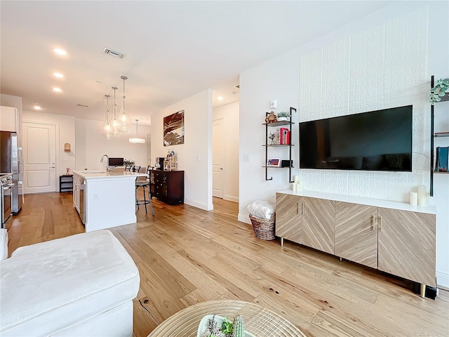 living area featuring visible vents, baseboards, light wood-style flooring, and recessed lighting