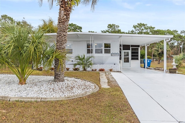 manufactured / mobile home featuring a front yard and a carport