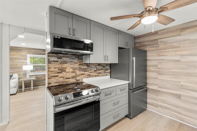 kitchen featuring ceiling fan, gray cabinets, appliances with stainless steel finishes, and light hardwood / wood-style flooring