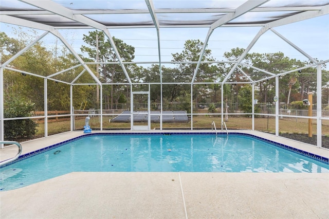 view of pool with glass enclosure and a patio area