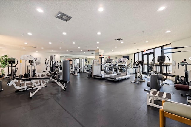 gym featuring floor to ceiling windows and a textured ceiling