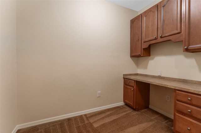 unfurnished office with dark colored carpet and built in desk