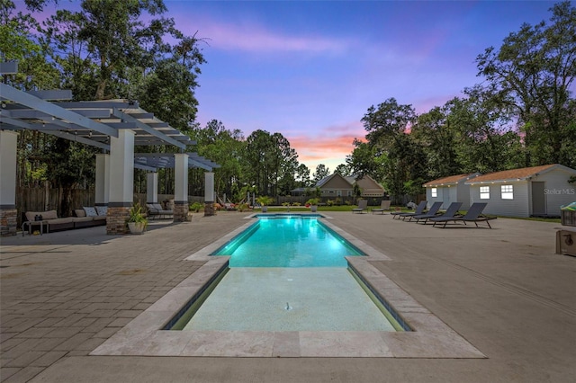 pool at dusk featuring an outbuilding, a pergola, and a patio