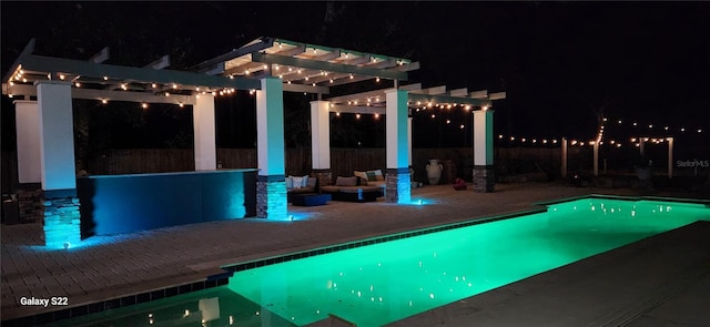 pool at night featuring a pergola and a patio