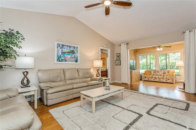 living room with ceiling fan, light wood-type flooring, and vaulted ceiling