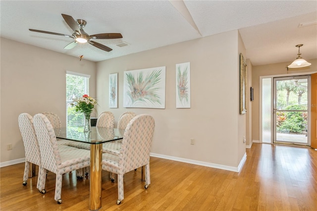 dining room with a textured ceiling, light wood-type flooring, and ceiling fan