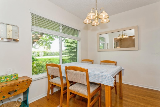 dining space with hardwood / wood-style flooring, a textured ceiling, a wealth of natural light, and a chandelier